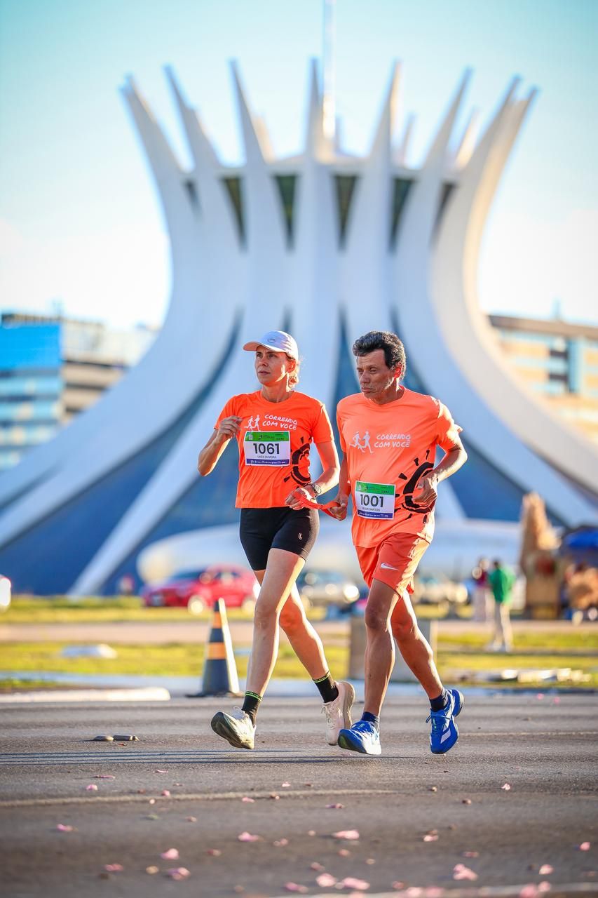 Dois corredores passando em frente à Catedral Metropolitana de Brasília durante uma corrida.